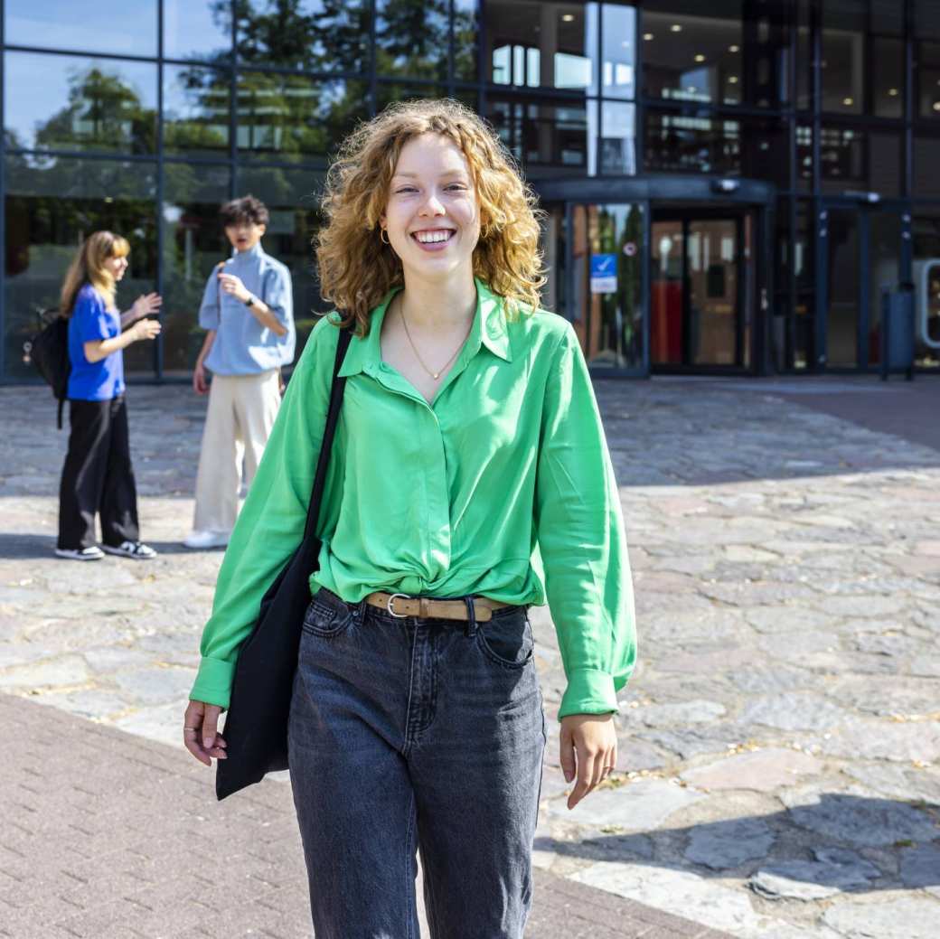 Student vrouw loopt buiten HAN-gebouw. Student Support Center. Campagne studiejaar 23-24. Fotoshoot 2023.