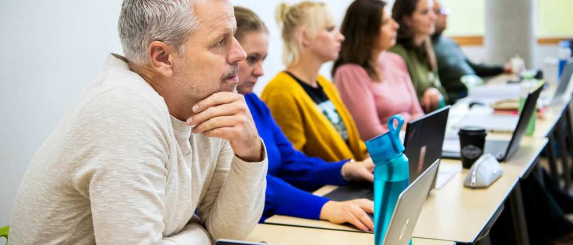 masterstudenten zitten op een rij aandachtig te luisteren naar de docent