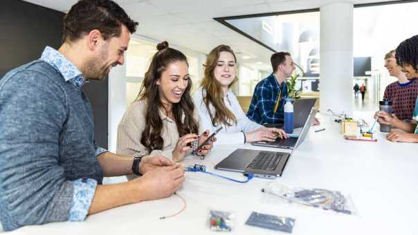 Docent en studenten cmd in overleg met prototype, lachend. 