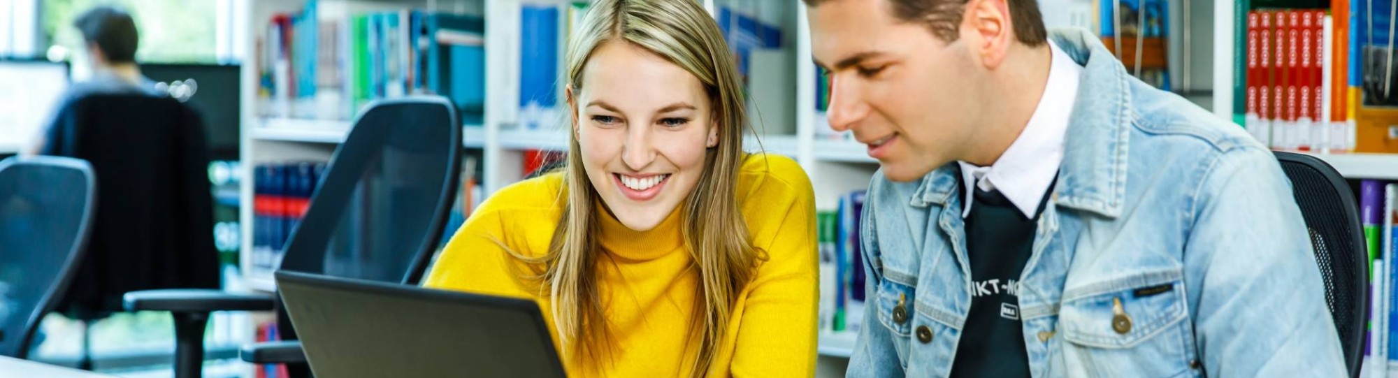 Twee HAN-studenten Leraar Nederlands werken achter één laptop in de mediatheek. 