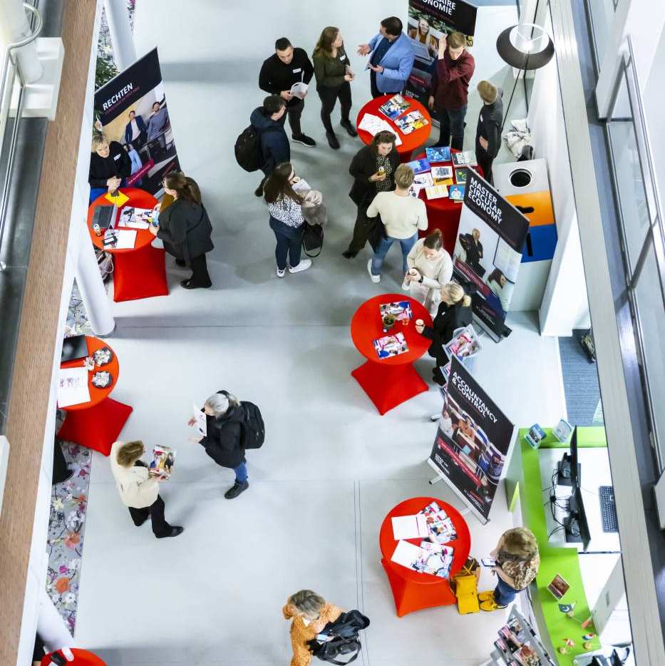 Adviseur achter een tafel op de open avond van Commerciële Economie duaal