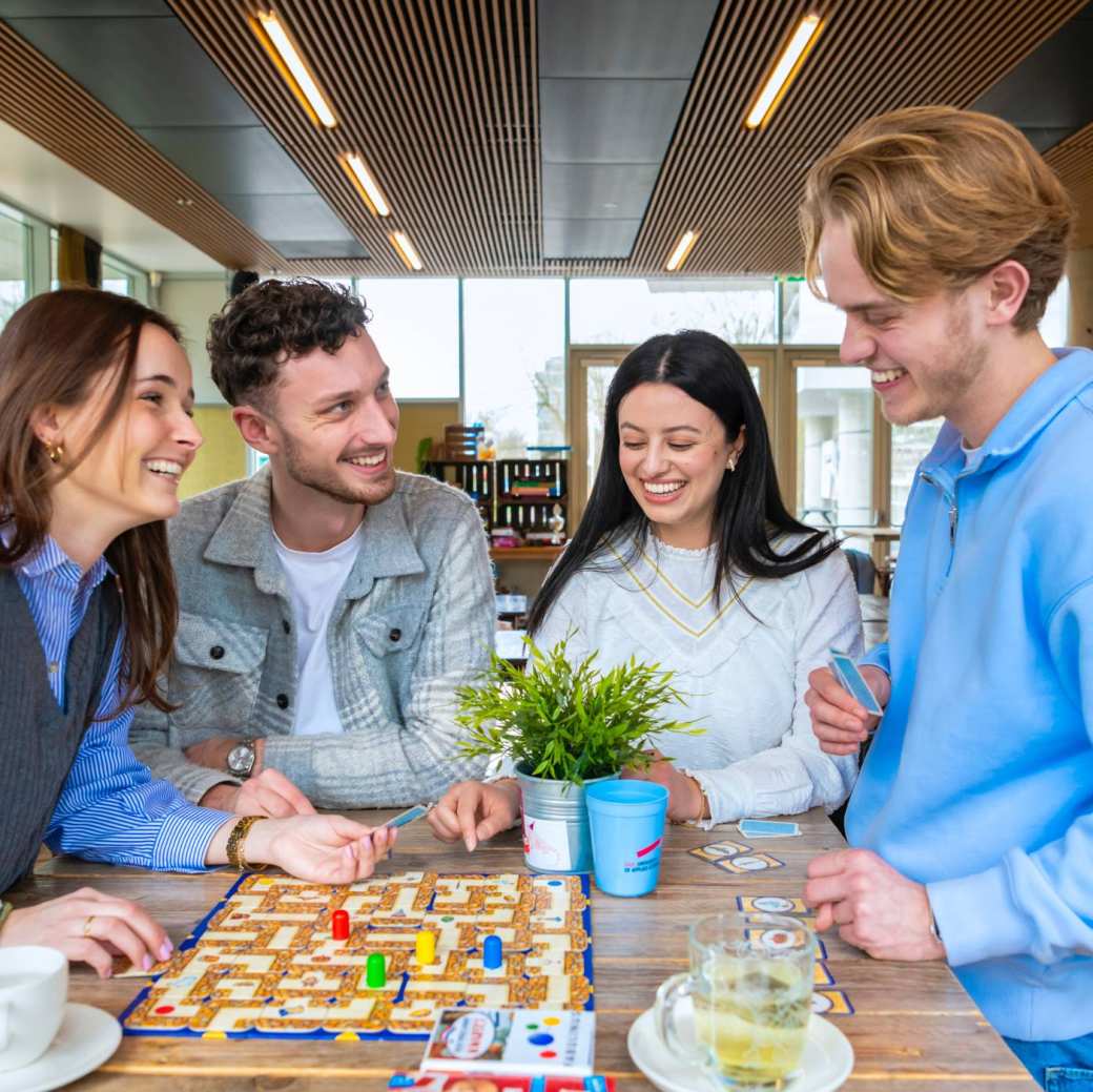 Studenten fietsen al kletsend over een brug naar school toe.