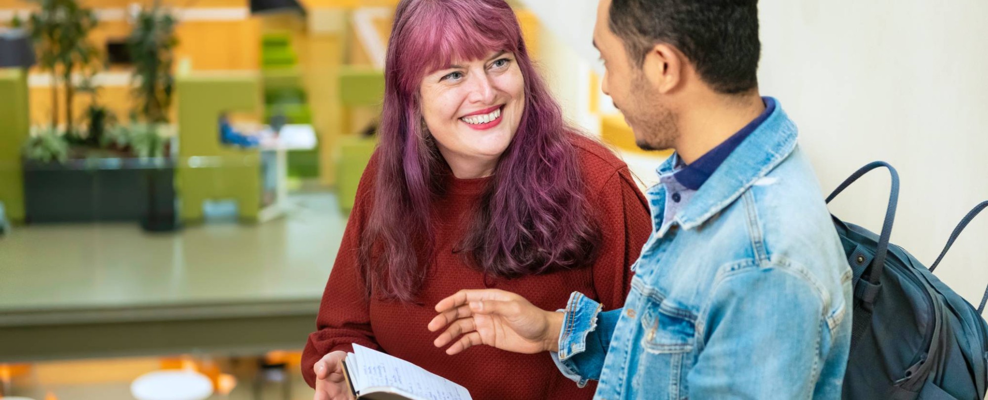 Twee studenten vertellen met elkaar terwijl de een een kladje in de hand heeft met geschreven tekst.
