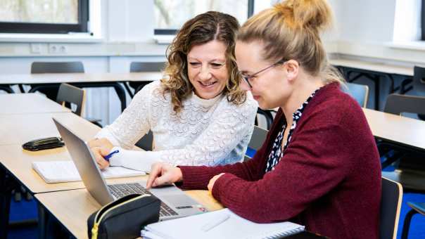 2 studenten zitten aan laptop en nemen samen lesstof door