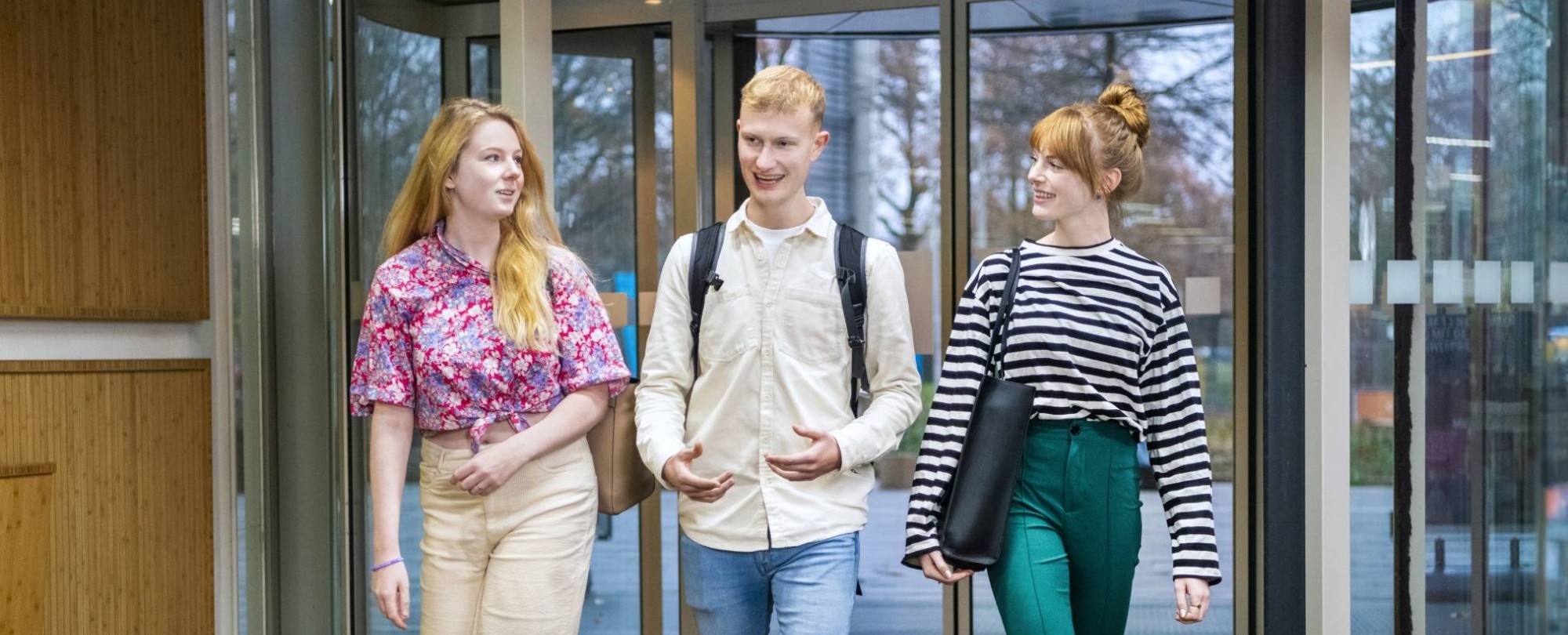 Drie leraar Geschiedenis studenten lopen de ingang van het i/o-gebouw in.