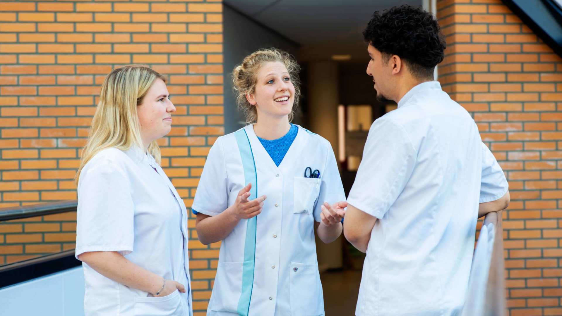 3 studenten in gesprek met elkaar op de brug