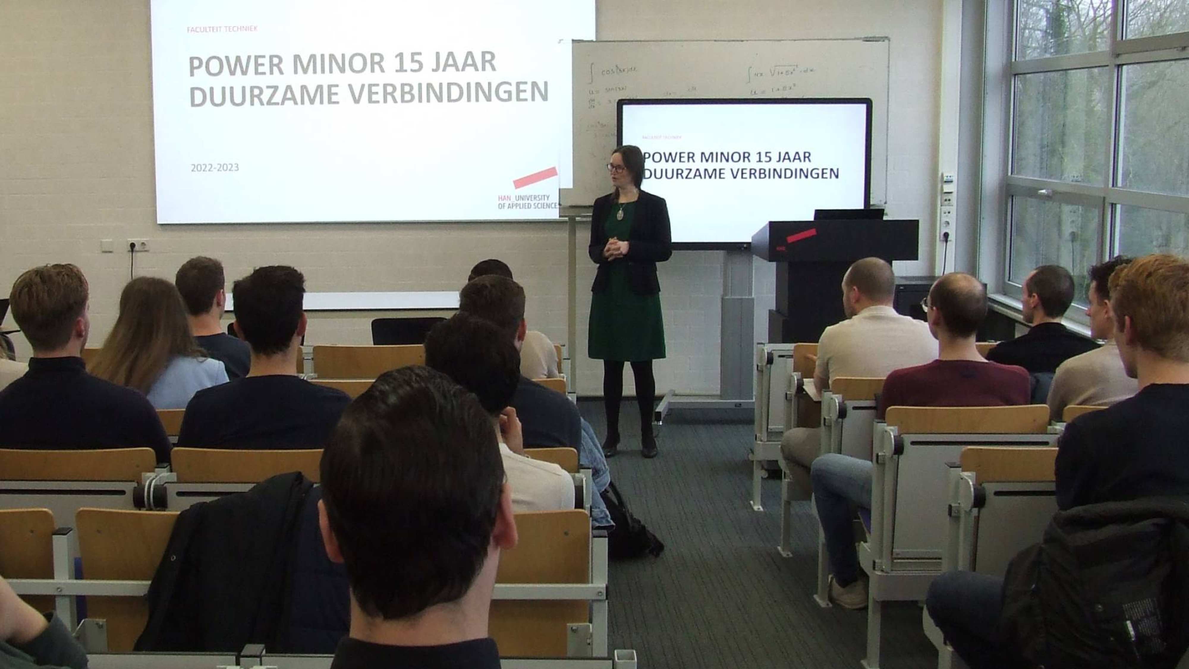 Docent die in een collegezaal de certificaatuitreiking van de Power Minor opent.