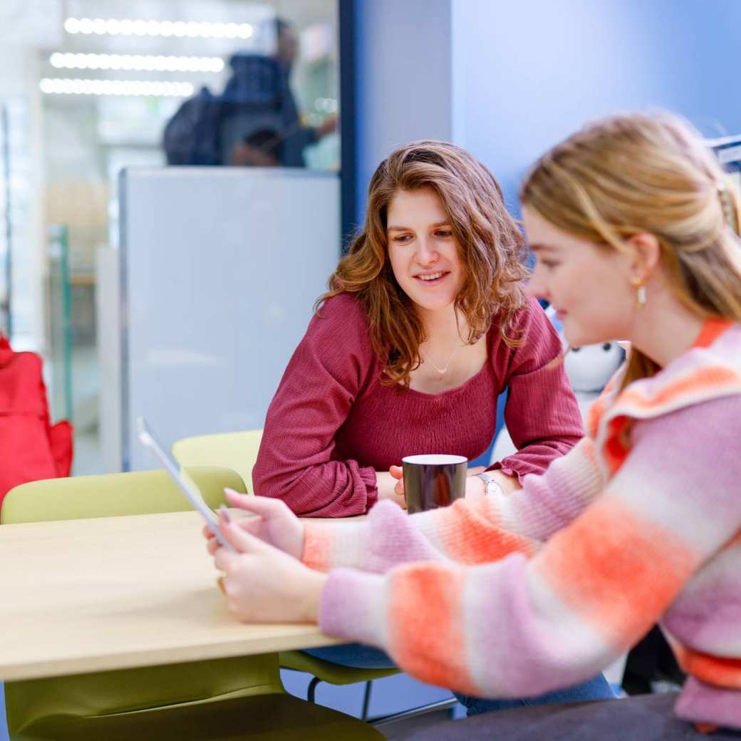 Twee communication & multimedia studenten studeren samen in de HAN bibliotheek