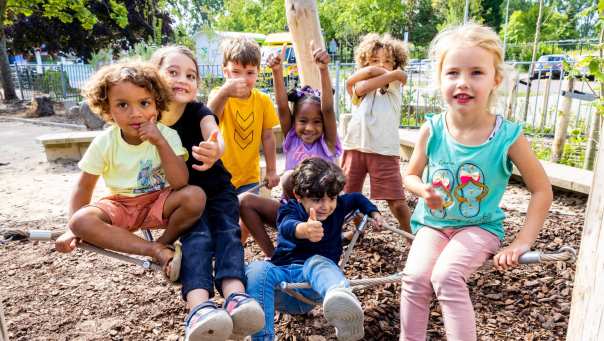 Zeven kinderen poseren buiten op het klimnet