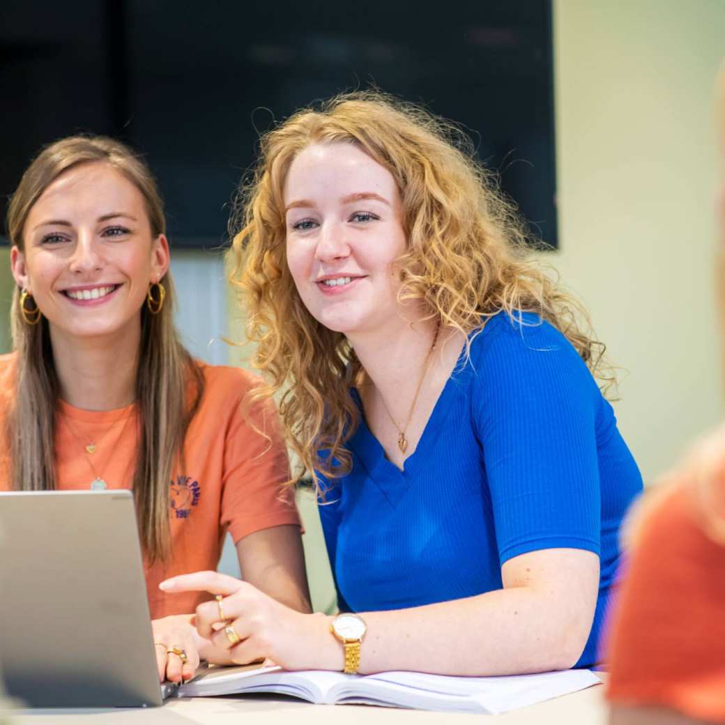 Verpleegkunde studenten kletsen en zitten samen aan een tafel tussen de lessen door