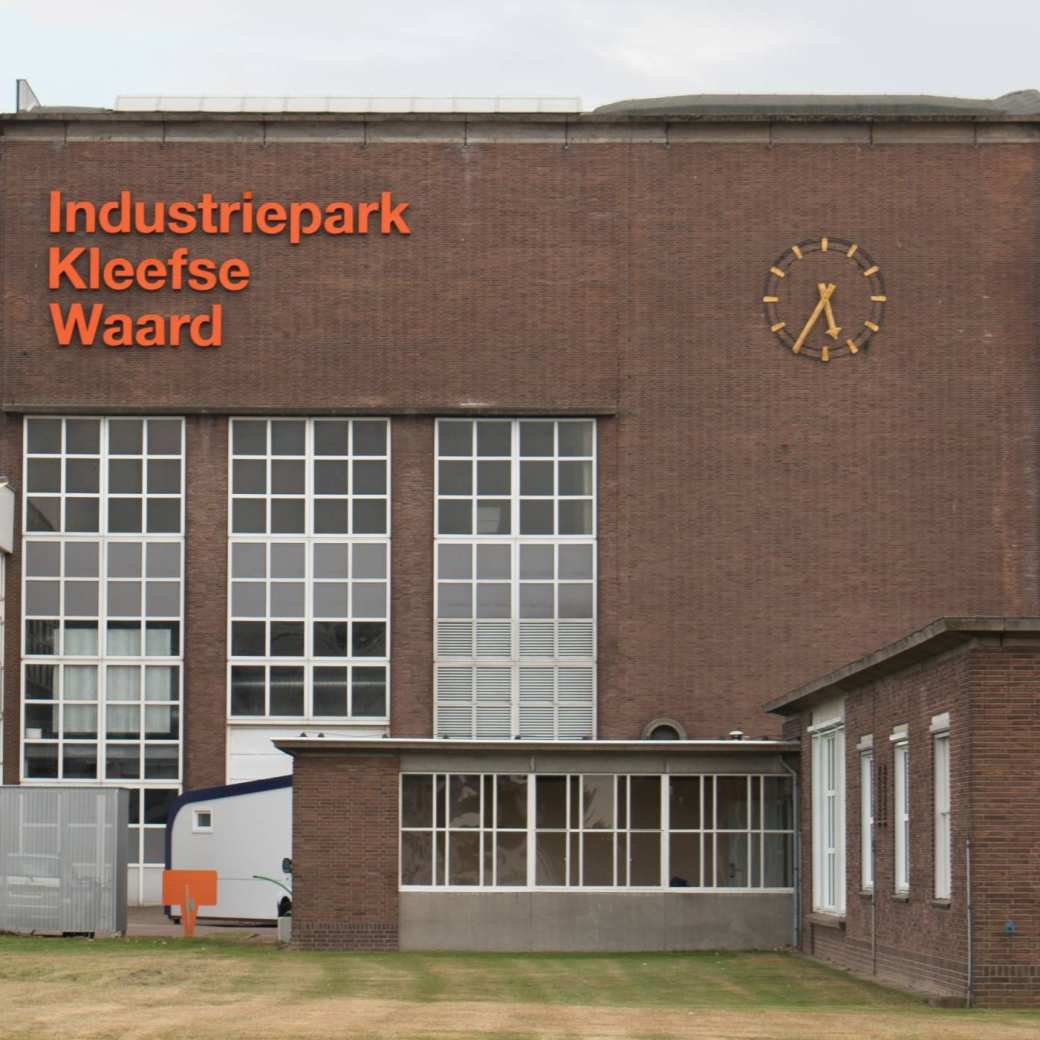 Gebouw op IPKW in Arnhem met klok en oranje letters 