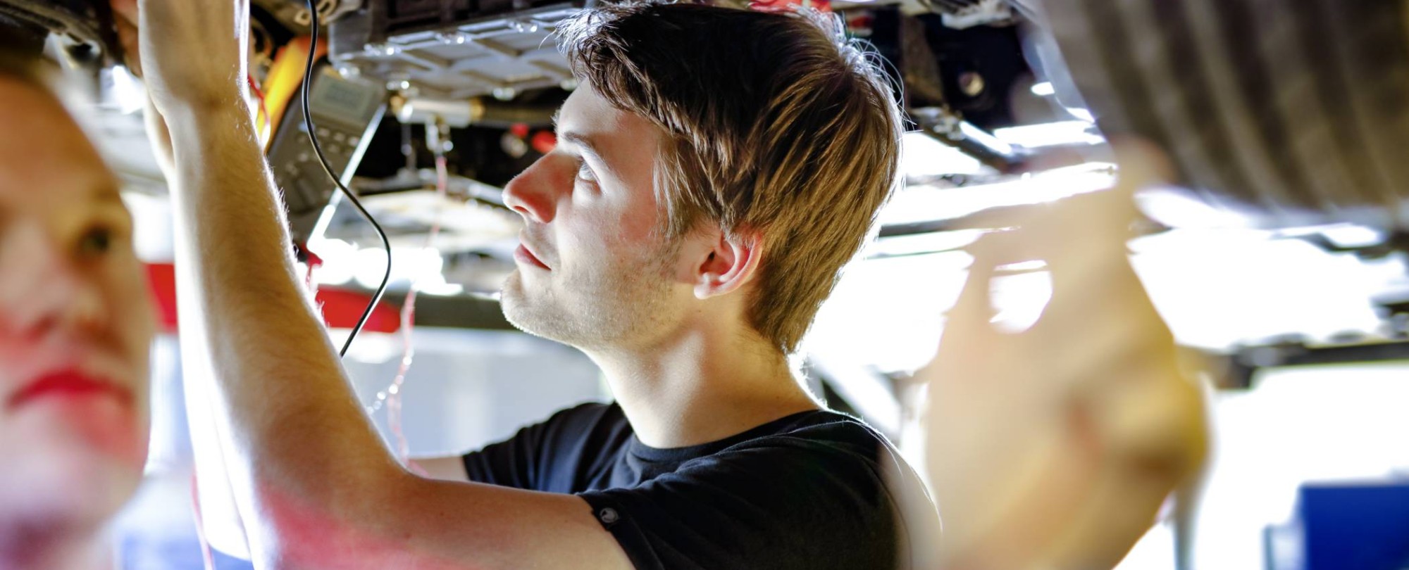 studenten werken aan auto op hefbrug