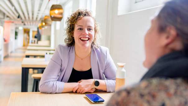 Vrouw in gesprek, moet lachen. Tijdens de cursus acute pijn service, in de kantine.