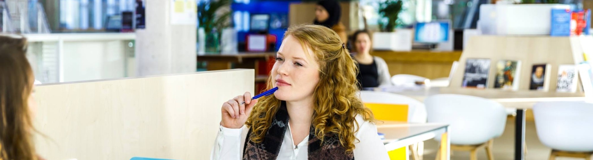 Student kijkt vragend naar haar medestudent die iets vertelt. 