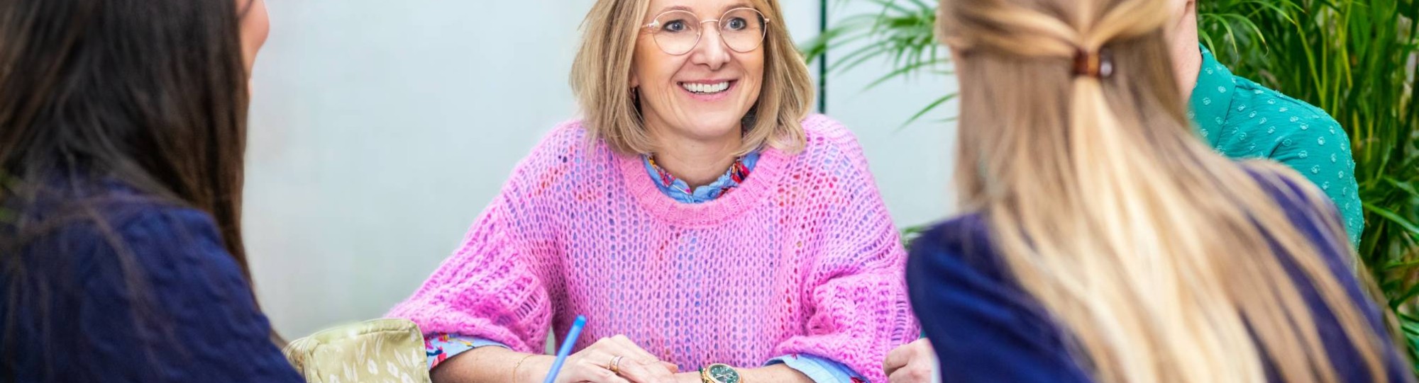 Een man en een vrouw kijkend naar een schrift op tafel in een klaslokaal