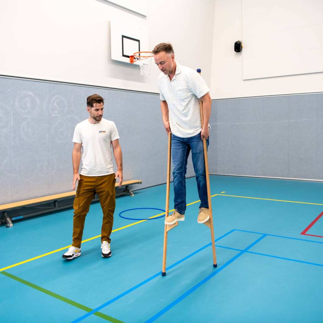 Twee studenten lopen met stelten tijdens les PMT deeltijd