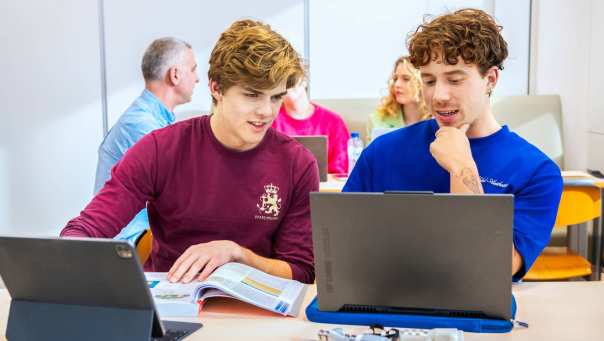 Studenten met laptop en boeken in leslokaal