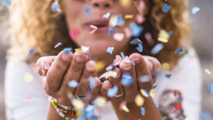 vrouw met confetti in handen en blaast