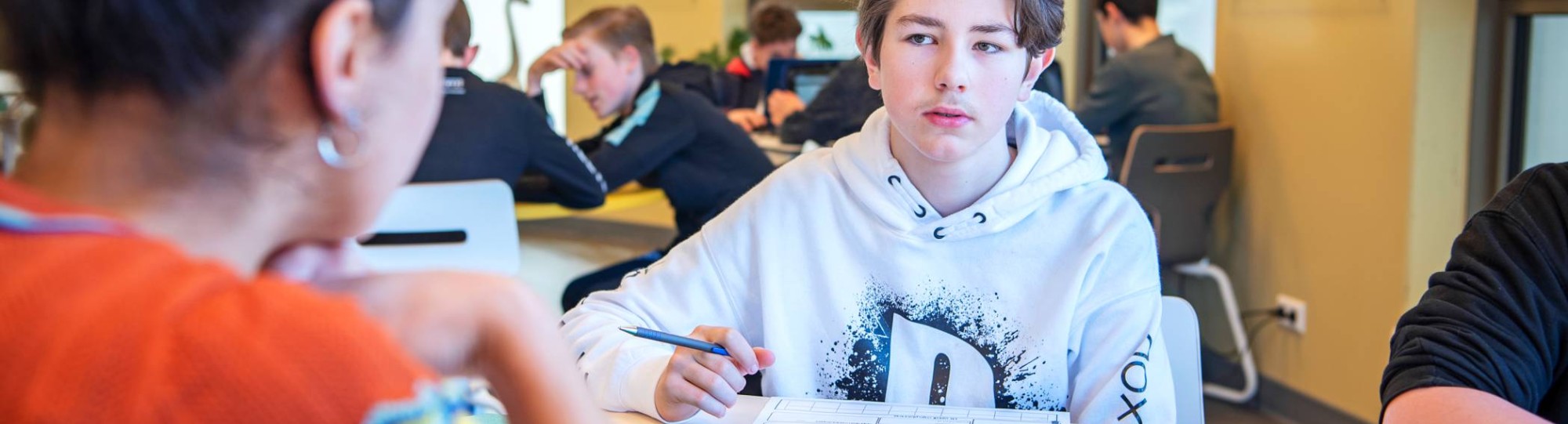 jongen luistert naar docent aan tafel