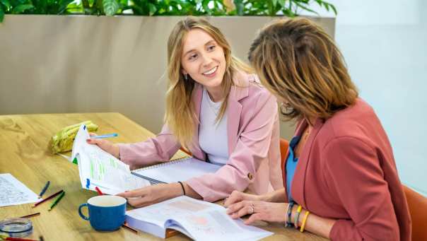 Twee studenten overleggen terwijl de een een boek vast heeft.