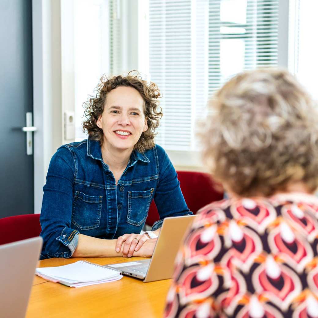 2 docenten zitten aan tafel in overleg