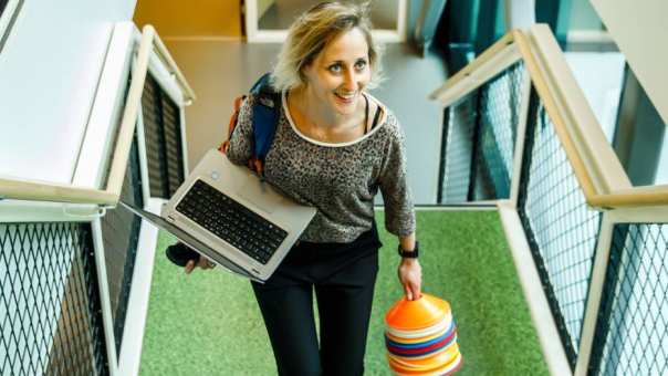 student loopt trap op met hoedjes en laptop