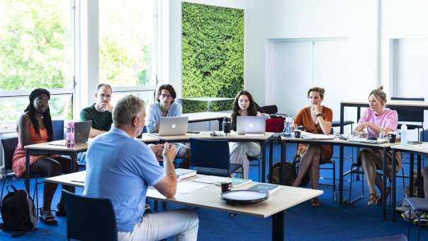 Studenten van de Master Social Work luisteren aandachtig terwijl de docent uitleg geeft.