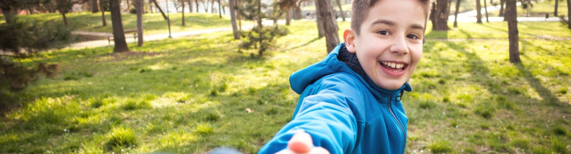 jongen in park die hand van ouder vasthoudt