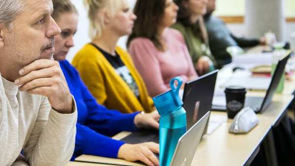 Student MOVEL kijkt vragend, terwijl hij in de klas zit naast zijn medestudenten.