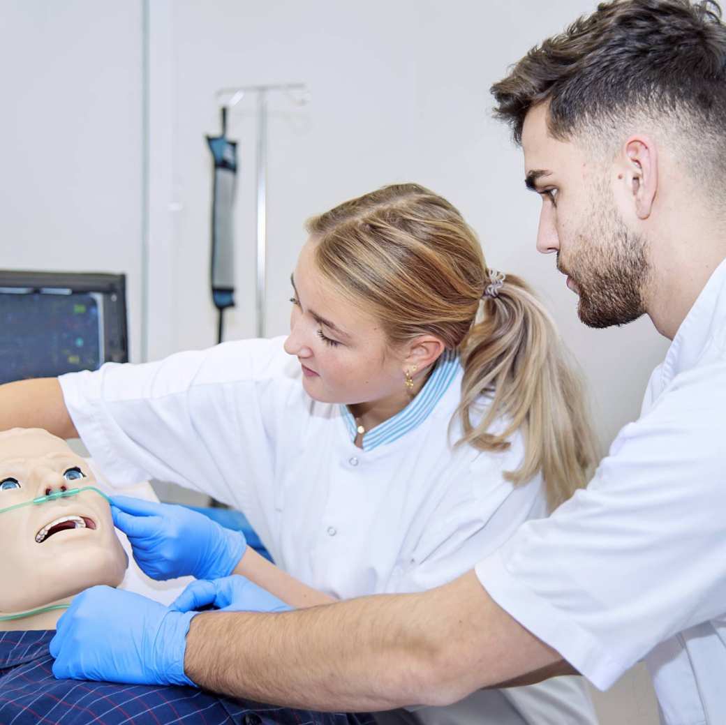 Verpleegkunde studenten aan het bed oefenen beademing bij pop-1