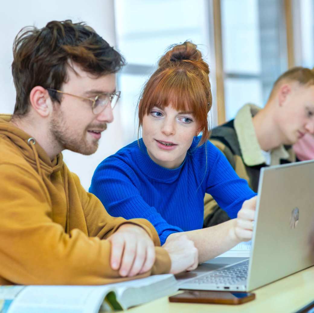 Twee studenten zitten in de mediatheek en kijken geconcentreerd naar de laptop.