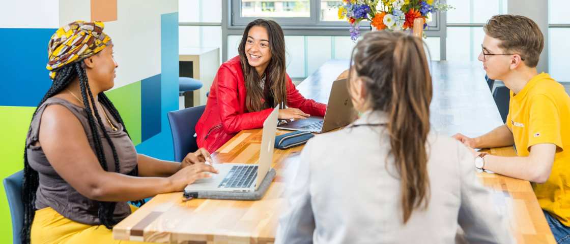 Lo-res. Groep van 4 studenten in overleg aan tafel in algemene ruimte HAN. 