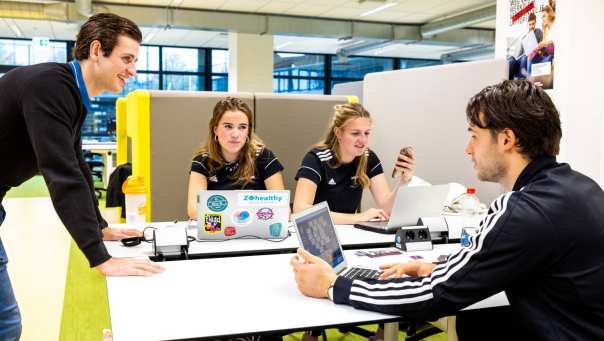 Studenten overleggen op een werkplek.