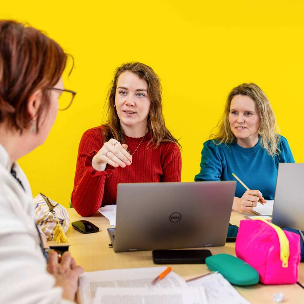 Deeltijd studenten zitten aan de tafel in het lokaal te praten.