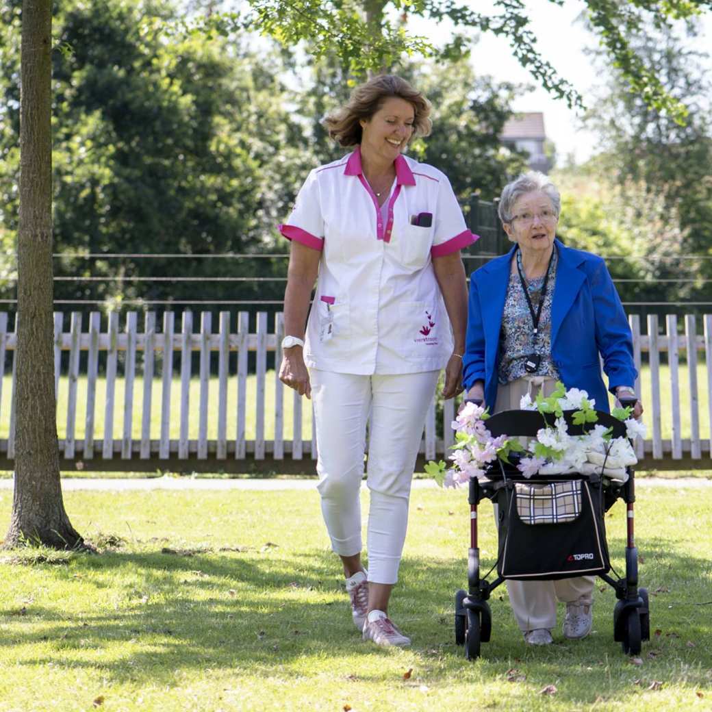 Zorgverlener wandelt met oudere dame in eigen omgeving