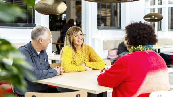 vrouw met gele trui lacht tijdens gesprek