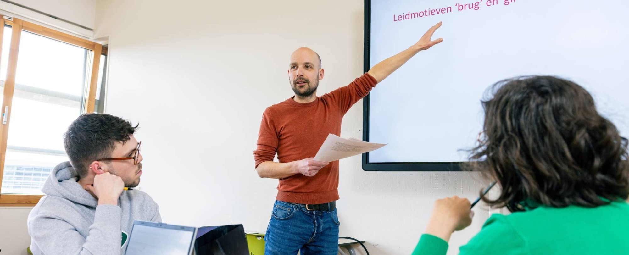 Leraar Nederlands staat voor de klas voor een whiteboard.