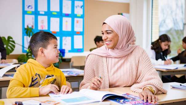 Juf geeft 1-op-1 instructie aan kind in de klas