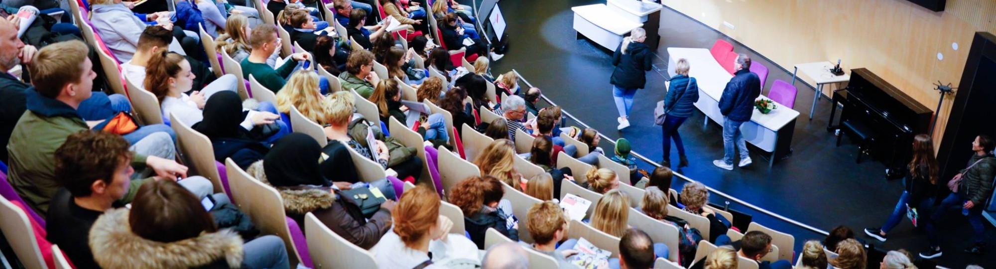 van bovenaf in auditorium met volle zaal voor presentatie