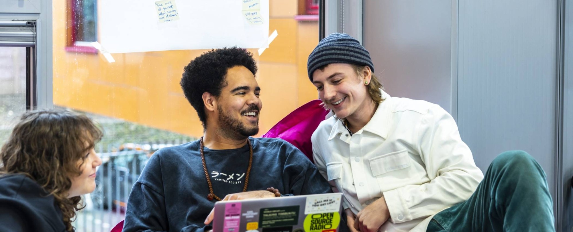 International Social Work. Drie studenten in gesprek. De middelste heeft een laptop. Ze zitten er relaxt bij.