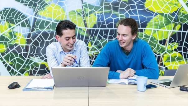 Studenten van de tweejarige hbo-opleiding werken samen achter de laptop en leren ook digitaal