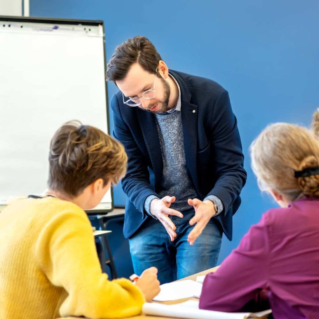 Docent Juri Krivzov geeft uitleg tijdens de les over onderzoek aan twee studenten van de Master Advanced Nursing Practice