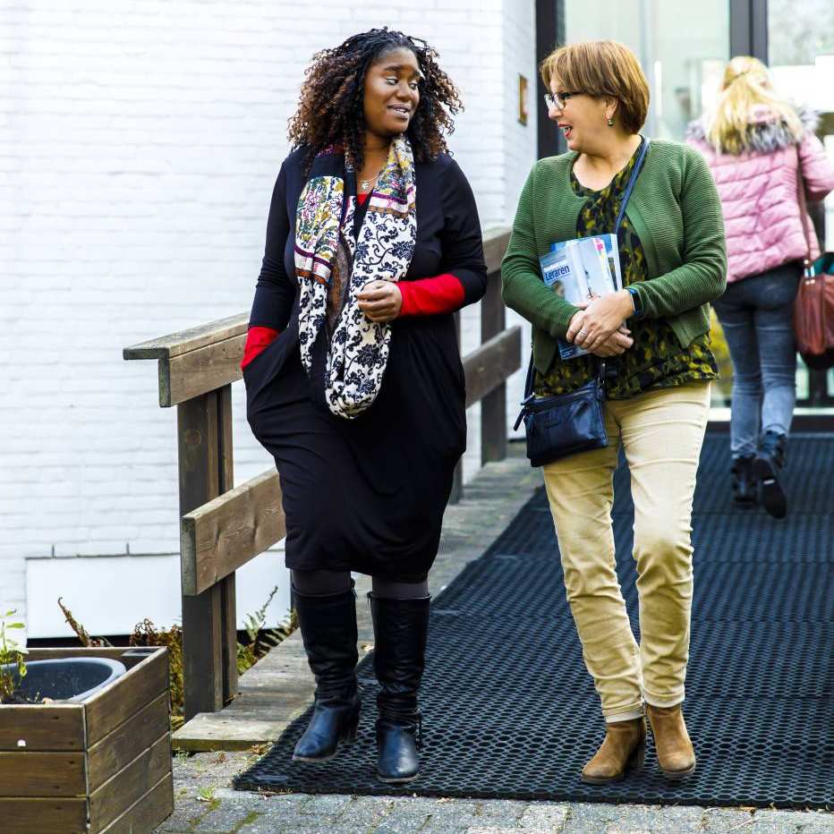 Twee vrouwen staan pratend naast elkaar voor de ingang