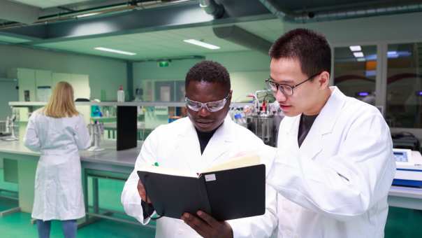 Studenten master Life Sciences Alain Barhasima en Dat Le werken in een biologielab. Op de rug Lisan Scholten